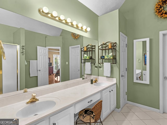 bathroom featuring a textured ceiling, double vanity, a sink, and tile patterned floors