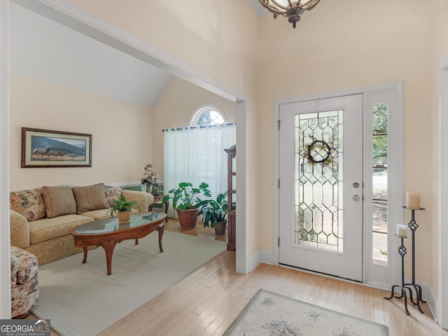 entryway featuring light wood-style floors, lofted ceiling, and baseboards