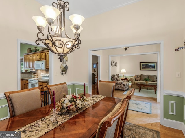 dining space featuring ornamental molding, a notable chandelier, light wood-style flooring, and baseboards