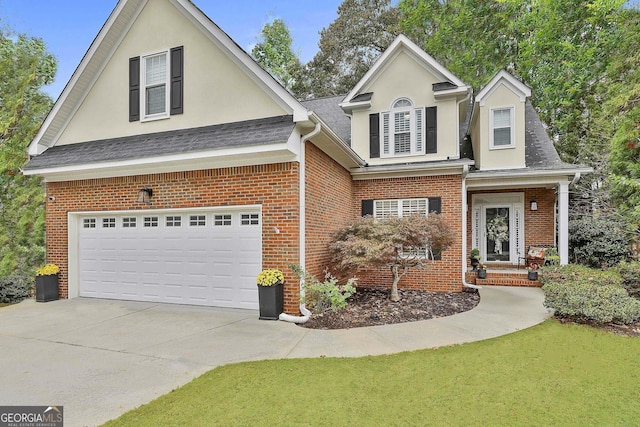 traditional-style home with an attached garage, brick siding, concrete driveway, and stucco siding