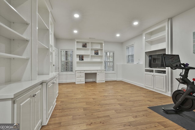 exercise room with built in study area, light wood-style flooring, and recessed lighting