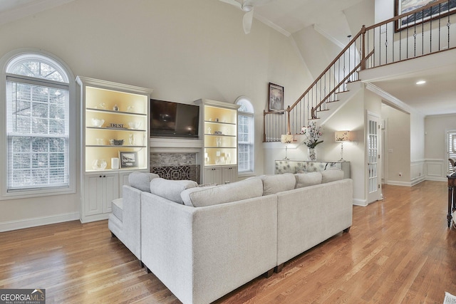 living area with high vaulted ceiling, light wood-style floors, a fireplace, and crown molding