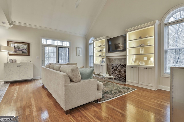 living room featuring a fireplace with flush hearth, plenty of natural light, and wood finished floors