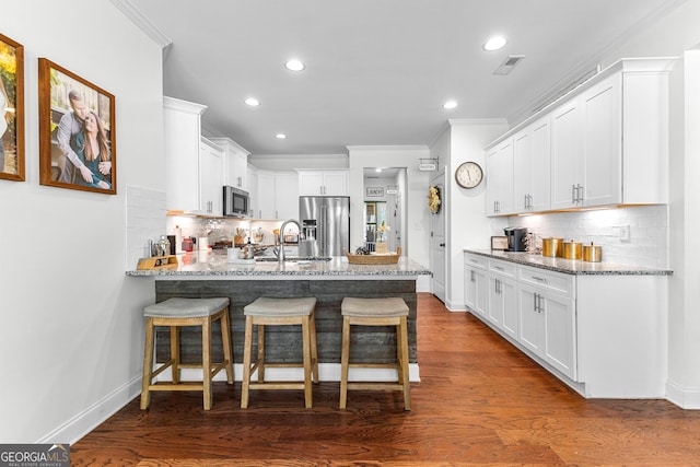 kitchen with ornamental molding, a peninsula, appliances with stainless steel finishes, and visible vents