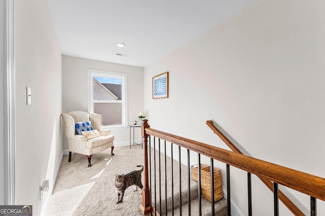 corridor featuring baseboards, an upstairs landing, visible vents, and light colored carpet