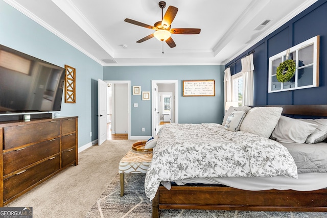 bedroom featuring light colored carpet, a tray ceiling, visible vents, and ornamental molding