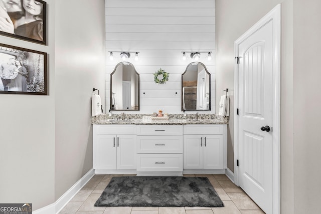 bathroom featuring baseboards, double vanity, a sink, and tile patterned floors