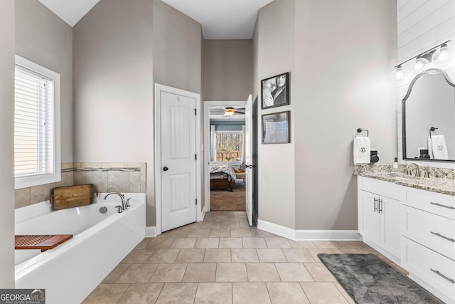 ensuite bathroom with a wealth of natural light, tile patterned floors, vanity, and a bath