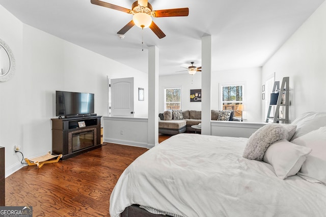 bedroom featuring a fireplace, ceiling fan, baseboards, and wood finished floors