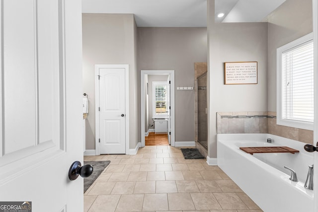 full bathroom featuring a wealth of natural light, tile patterned floors, a shower stall, and a bath