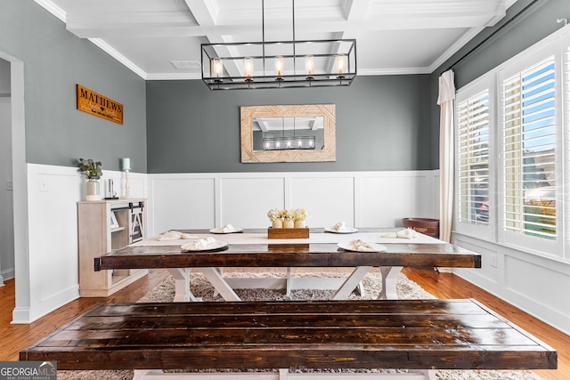 dining area featuring crown molding, coffered ceiling, wood finished floors, and a healthy amount of sunlight