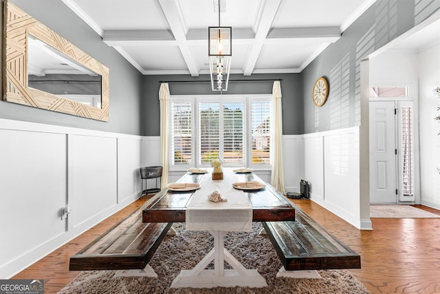 dining area featuring coffered ceiling, wood finished floors, beam ceiling, and a decorative wall