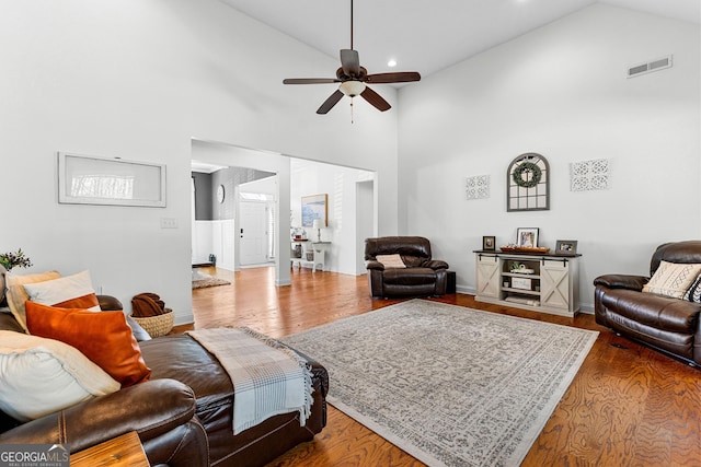 living area featuring ceiling fan, high vaulted ceiling, wood finished floors, visible vents, and baseboards