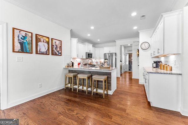 kitchen featuring stainless steel appliances, crown molding, a sink, and a peninsula