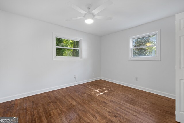 unfurnished room with ceiling fan, wood finished floors, a wealth of natural light, and baseboards