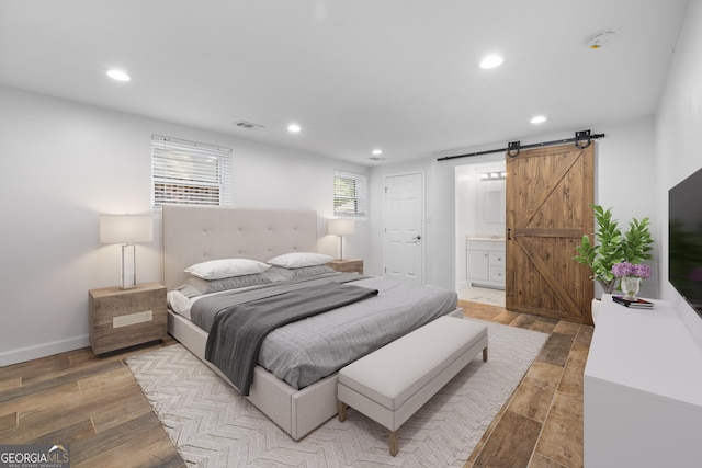 bedroom featuring light wood finished floors, a barn door, visible vents, and recessed lighting