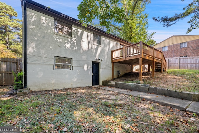 back of property featuring a fenced backyard, brick siding, a deck, and stairs