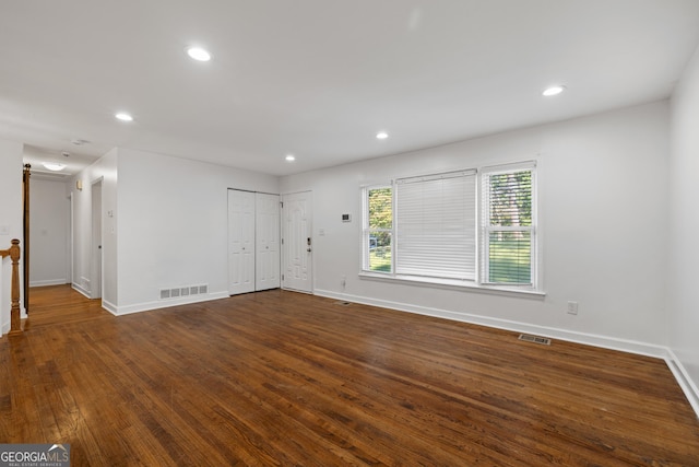 unfurnished room with baseboards, visible vents, dark wood-style flooring, and recessed lighting