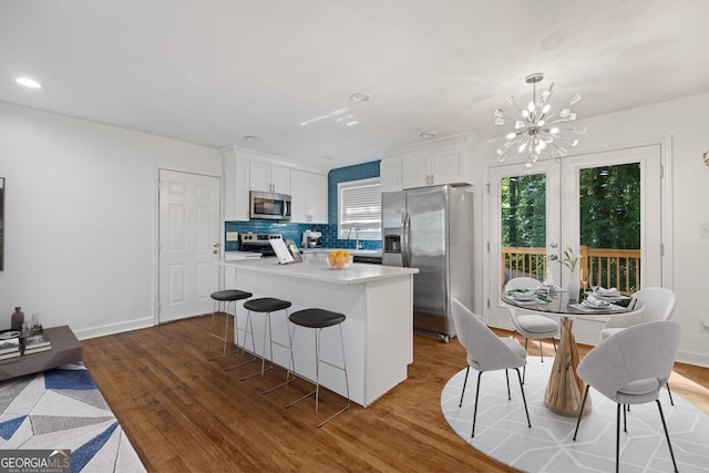 kitchen with white cabinets, a healthy amount of sunlight, stainless steel appliances, and backsplash