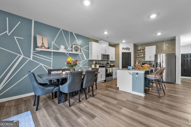 dining space featuring light wood finished floors and recessed lighting