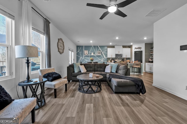 living room featuring recessed lighting, a ceiling fan, visible vents, baseboards, and light wood-type flooring