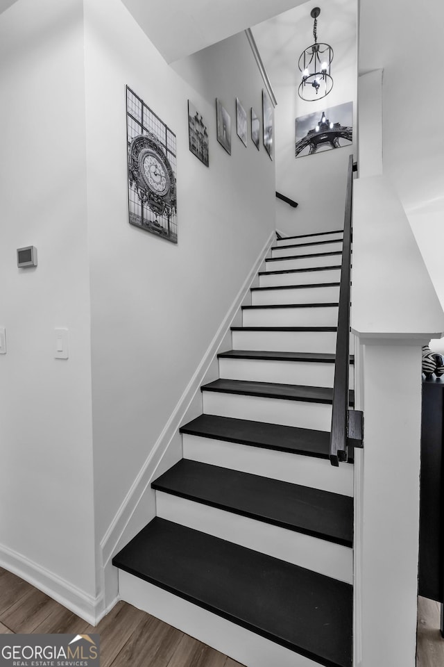 stairway with a notable chandelier, baseboards, and wood finished floors