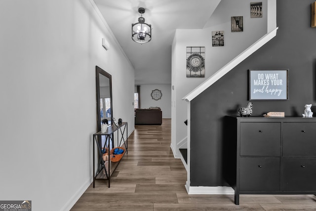 hall featuring baseboards, a chandelier, and wood finished floors