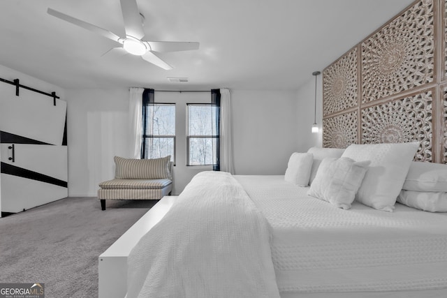 carpeted bedroom with a barn door, visible vents, and a ceiling fan