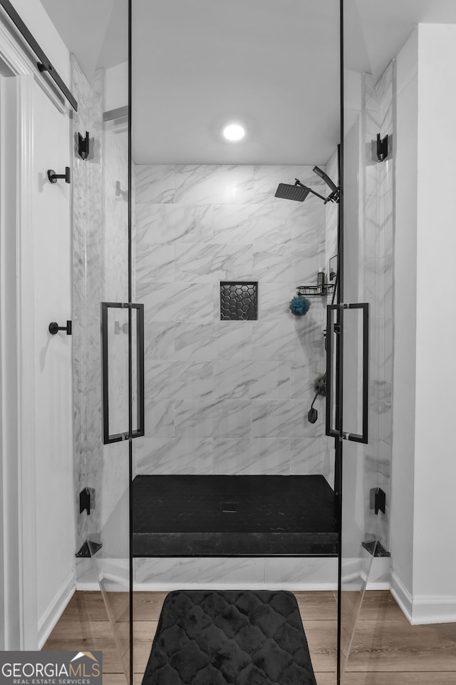 bathroom with a stall shower and wood finished floors