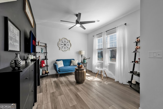 sitting room with a ceiling fan, baseboards, visible vents, and light wood finished floors