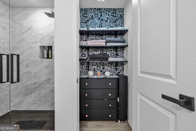 interior details with a marble finish shower and wood finished floors