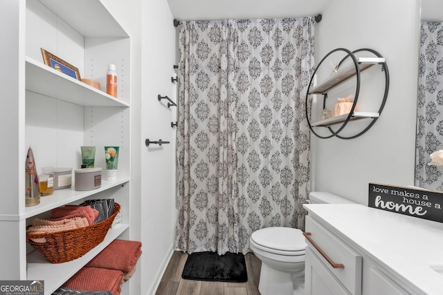 bathroom with toilet, a shower with curtain, wood finished floors, and vanity