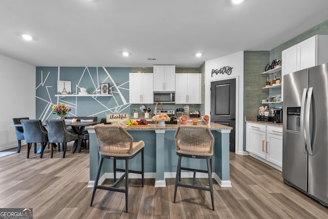 kitchen with white cabinets, light wood-type flooring, appliances with stainless steel finishes, and open shelves