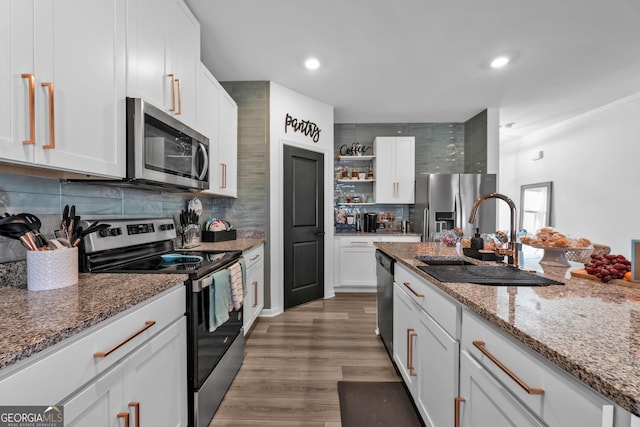 kitchen featuring open shelves, stainless steel appliances, decorative backsplash, white cabinets, and a sink