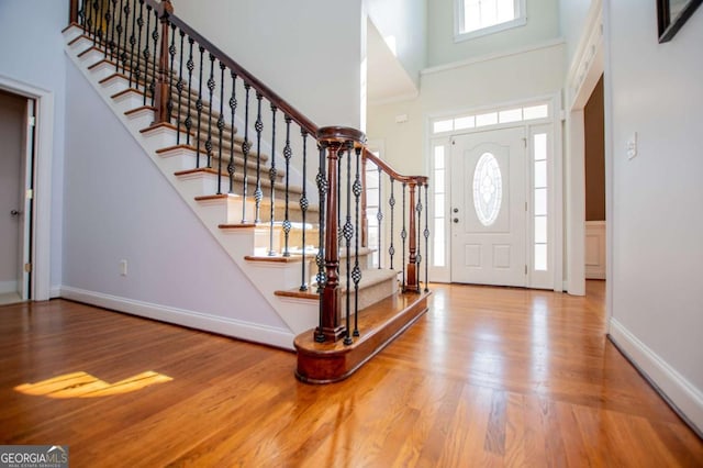 foyer featuring stairs, a high ceiling, wood finished floors, and baseboards