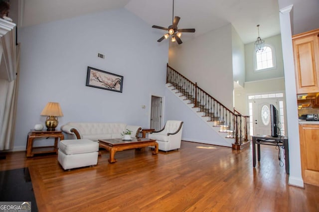 living room featuring stairway, a ceiling fan, wood finished floors, high vaulted ceiling, and baseboards