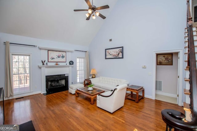 living room featuring wood finished floors, a wealth of natural light, a fireplace with flush hearth, and visible vents