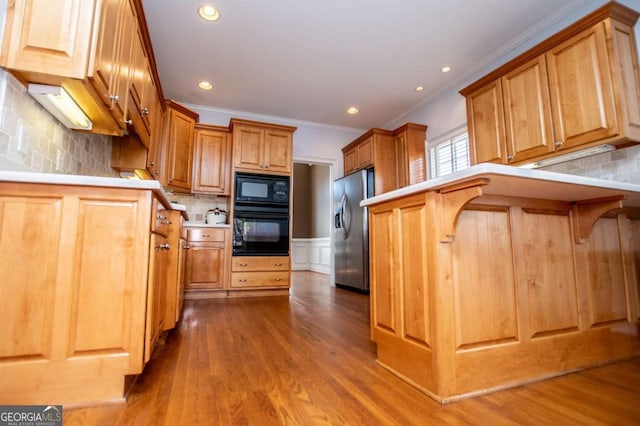 kitchen featuring brown cabinets, crown molding, decorative backsplash, wood finished floors, and black appliances