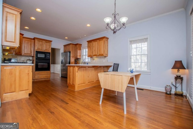 kitchen with light wood-style flooring, a peninsula, black appliances, a kitchen bar, and crown molding