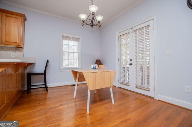 dining area with light wood finished floors, french doors, a chandelier, and crown molding