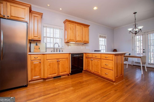 kitchen featuring a peninsula, black dishwasher, stainless steel refrigerator, and light wood-style flooring