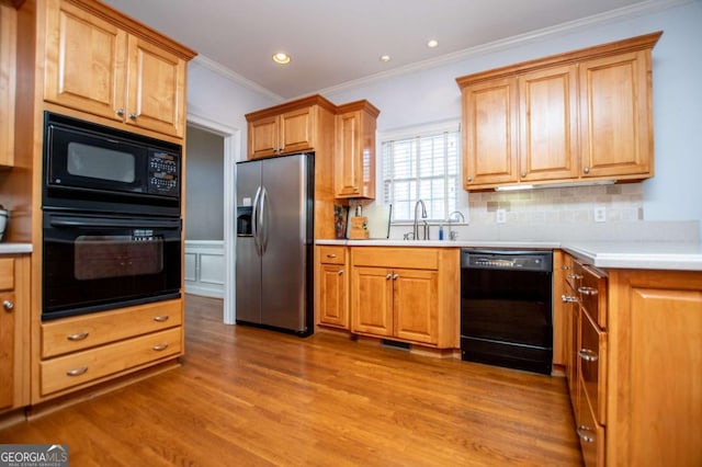 kitchen with wood finished floors, light countertops, backsplash, black appliances, and crown molding