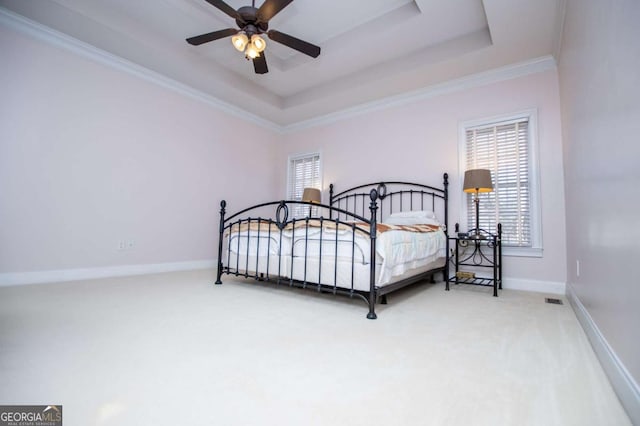 carpeted bedroom featuring a raised ceiling, visible vents, ornamental molding, ceiling fan, and baseboards