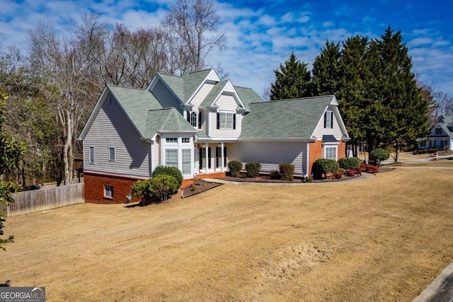 traditional-style home with driveway, a front lawn, fence, and brick siding