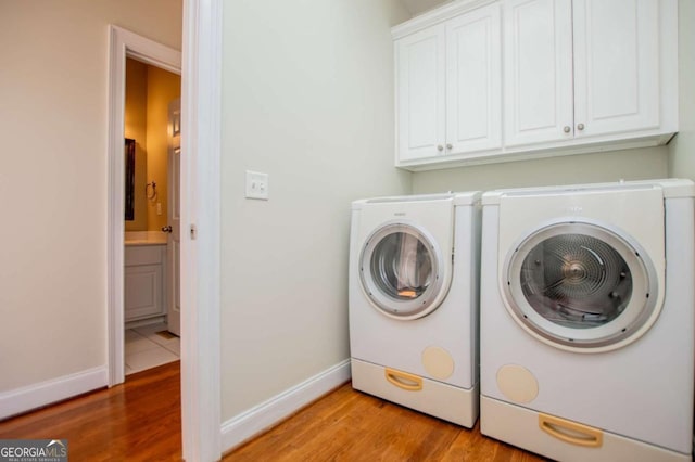 washroom with washer and dryer, cabinet space, light wood-style flooring, and baseboards