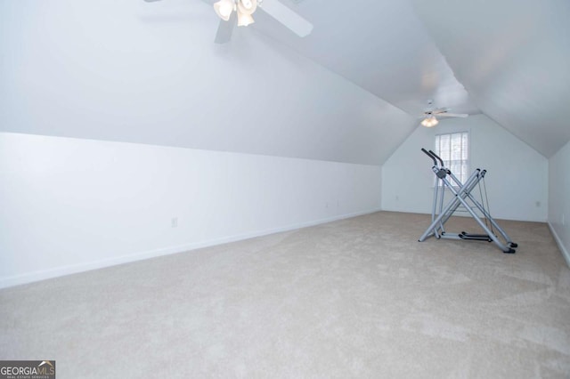 exercise area with lofted ceiling, light carpet, baseboards, and a ceiling fan