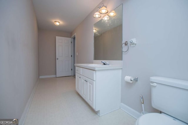 bathroom with toilet, baseboards, and vanity