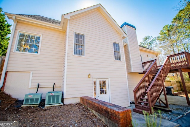 rear view of property with central air condition unit, stairs, a chimney, and a wooden deck