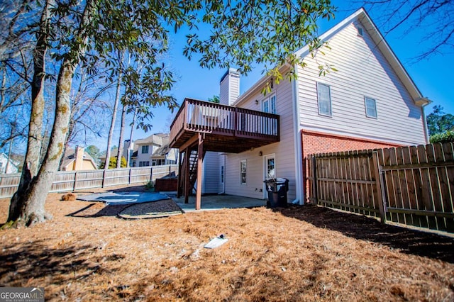 rear view of house featuring a patio, a chimney, a fenced backyard, a wooden deck, and stairs