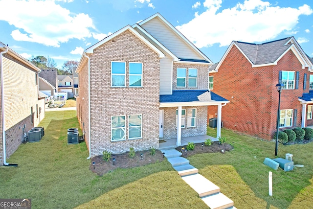 traditional-style home featuring central air condition unit, covered porch, a front yard, and brick siding